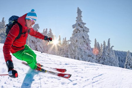 Foto de Esquiador esquiando cuesta abajo en las altas montañas contra el cielo azul
. - Imagen libre de derechos