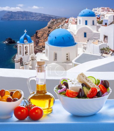 Foto de Greek food against famous churches in Oia village on Santorini island in Greece - Imagen libre de derechos