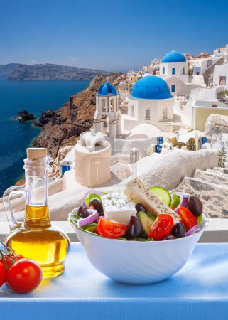 Foto de Greek food against famous churches in Oia village on Santorini island in Greece - Imagen libre de derechos