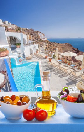 Foto de Greek food against luxury resort with swimming pool in Oia village on Santorini island in Greece - Imagen libre de derechos