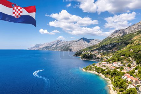 Croatian flag against coastline with Brela town and Adriatic sea in Makarska riviera, Dalmatia, Croatia