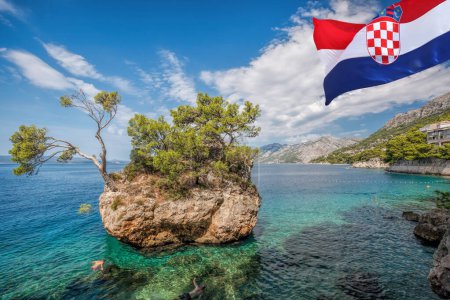Punta Rata playa con bandera croata contra isla de piedra en Brela, Makarska, Dalmacia, Croacia