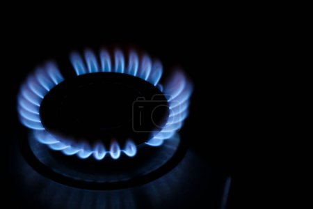 Téléchargez les photos : Table de cuisson au gaz avec flamme brûlante dans l'obscurité, gros plan. Espace pour le texte - en image libre de droit