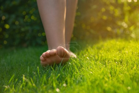 Foto de Adolescente caminando descalza sobre hierba verde al aire libre, de cerca. Espacio para texto - Imagen libre de derechos