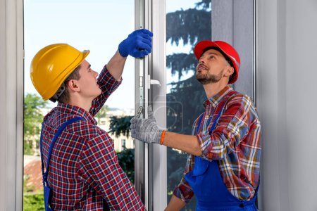 Foto de Trabajadores en uniforme instalando ventana de plástico en interiores - Imagen libre de derechos