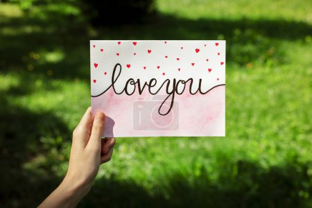 Foto de Mujer con tarjeta con frase Love You al aire libre, primer plano - Imagen libre de derechos