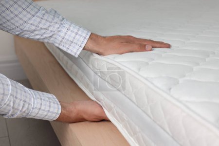 Téléchargez les photos : Man touching soft white mattress indoors, closeup - en image libre de droit
