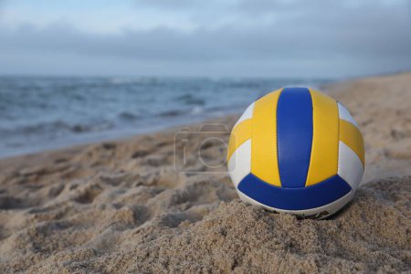 Téléchargez les photos : Ballon de volley coloré sur sable près de la mer. Espace pour le texte - en image libre de droit