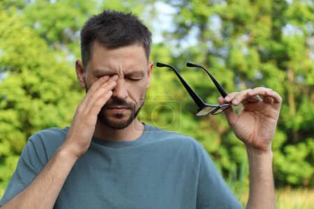 Foto de Hombre que sufre de fatiga ocular al aire libre en un día soleado - Imagen libre de derechos