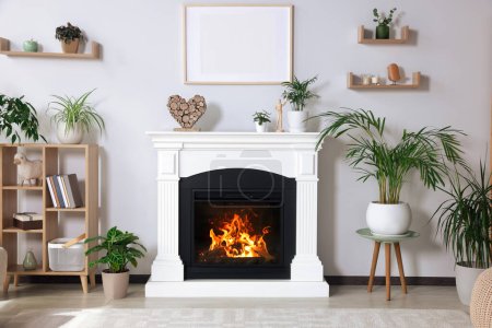 Photo for Stylish living room interior with fireplace, houseplants and cabinet - Royalty Free Image