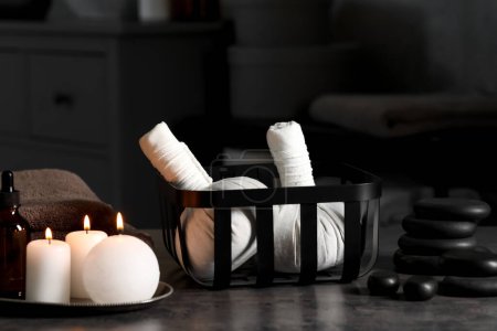 Photo for Herbal massage bags, burning candles and stones on grey table. Spa products - Royalty Free Image