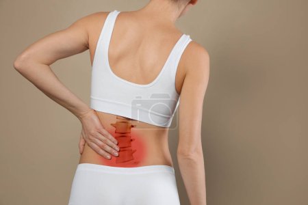 Foto de Mujer que sufre de dolor en la espalda sobre fondo beige, primer plano - Imagen libre de derechos