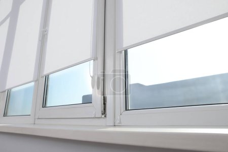 Photo for Large window with white roller blinds indoors - Royalty Free Image