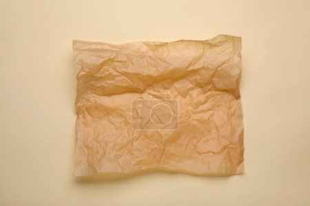 Téléchargez les photos : Feuille de papier sulfurisé froissé sur fond beige, vue de dessus - en image libre de droit