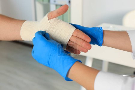 Foto de Médico aplicando vendaje médico en la mano del paciente en el hospital, primer plano - Imagen libre de derechos