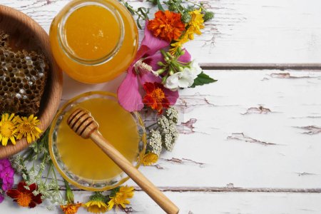 Foto de Deliciosa miel con peines y diferentes flores sobre mesa de madera blanca, puesta plana. Espacio para texto - Imagen libre de derechos