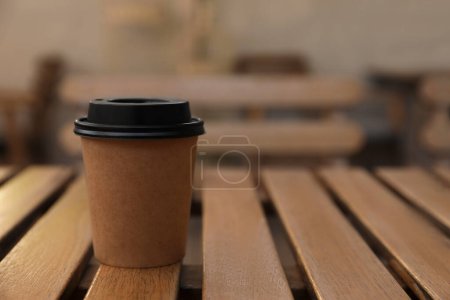 Photo for Takeaway paper cup with coffee on wooden table indoors, closeup. Space for text - Royalty Free Image