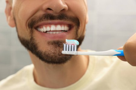 Foto de Hombre sosteniendo cepillo con pasta de dientes contra fondo borroso, primer plano - Imagen libre de derechos