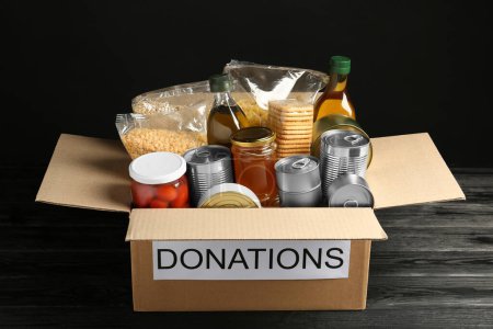 Foto de Caja de donaciones con comida sobre mesa de madera negra - Imagen libre de derechos