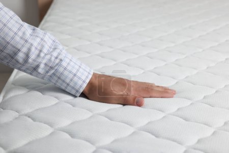 Photo for Man touching soft white mattress indoors, closeup - Royalty Free Image