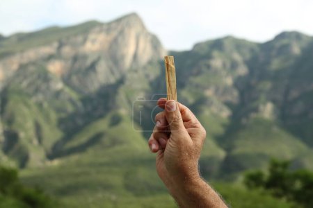 Téléchargez les photos : Homme tenant palo santo bâton dans les hautes montagnes, gros plan - en image libre de droit