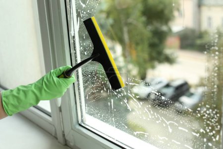 Téléchargez les photos : Woman cleaning glass with squeegee indoors, closeup - en image libre de droit