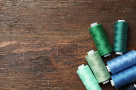 Foto de Diferentes hilos de costura de colores en la mesa de madera, planas. Espacio para texto - Imagen libre de derechos