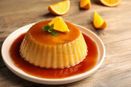 Photo for Delicious pudding with caramel, orange and mint on wooden table - Royalty Free Image