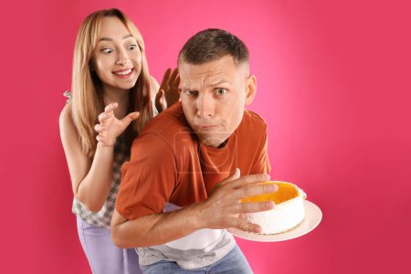 Photo for Greedy man hiding tasty cake from woman on pink background - Royalty Free Image