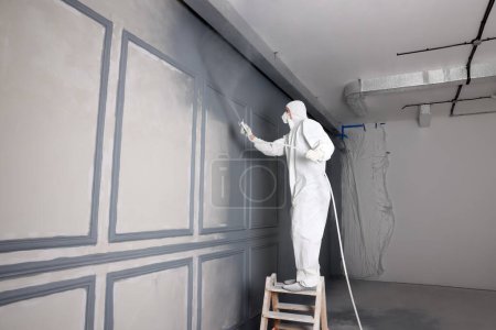 Photo for Decorator dyeing wall in grey color with spray paint indoors - Royalty Free Image