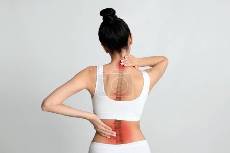Photo for Woman suffering from pain in back on light background - Royalty Free Image