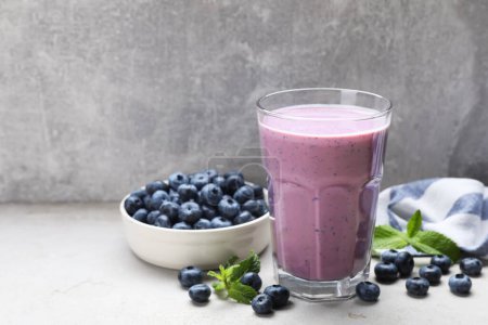 Glass of freshly made blueberry smoothie on light grey table. Space for text