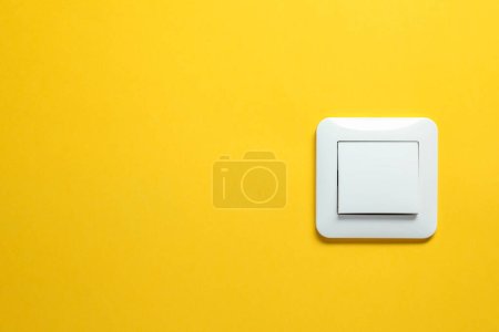 Modern plastic light switch on orange background. Space for text