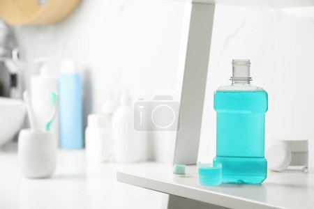 Foto de Botella de enjuague bucal en estante blanco en baño, espacio para texto - Imagen libre de derechos