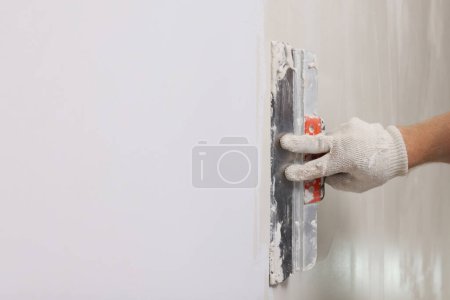 Photo for Worker plastering wall with putty knife indoors, closeup. Space for text - Royalty Free Image