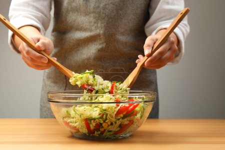 Photo for Woman making tasty salad with Chinese cabbage at wooden table, closeup - Royalty Free Image
