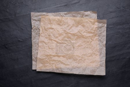 Téléchargez les photos : Feuilles de papier cuisson sur table noire, vue de dessus - en image libre de droit