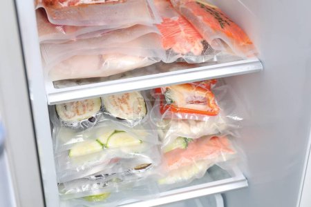 Téléchargez les photos : Sacs à vide avec différents produits au réfrigérateur. Stockage alimentaire - en image libre de droit