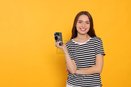 Photo for Young woman with camera on yellow background, space for text. Interesting hobby - Royalty Free Image