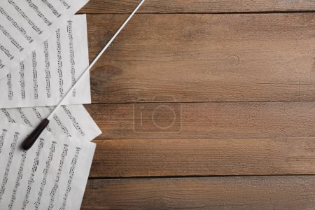 Foto de Bastón de director y partitura sobre mesa de madera, plano. Espacio para texto - Imagen libre de derechos