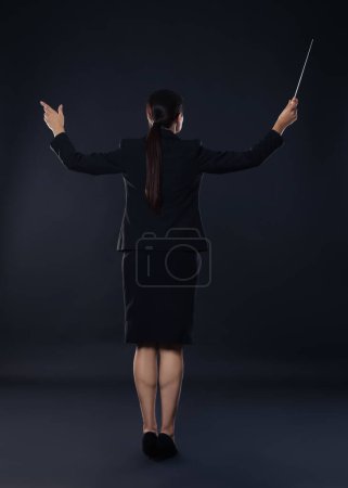 Foto de Conductor profesional con bastón sobre fondo oscuro, vista trasera - Imagen libre de derechos