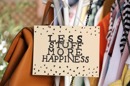Photo for Plate with words Less Stuff More Happiness near bags and clothes - Royalty Free Image
