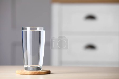 Glass of clean water on wooden table indoors, space for text