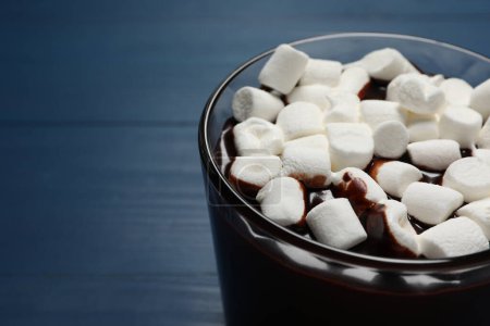 Photo for Glass cup of delicious hot chocolate with marshmallows on blue wooden table, closeup. Space for text - Royalty Free Image