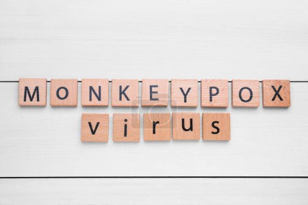 Téléchargez les photos : Words Virus de la variole du singe fait de carrés sur une table en bois blanc, à plat - en image libre de droit