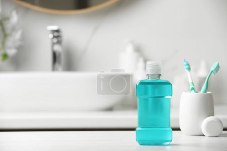 Foto de Enjuague bucal, cepillos de dientes y hilo dental en la encimera blanca en el baño. Espacio para texto - Imagen libre de derechos