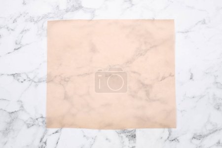 Téléchargez les photos : Feuille de papier cuisson sur table en marbre blanc, vue de dessus - en image libre de droit