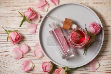 Photo for Flat lay composition with essential rose oil and flowers on white wooden table - Royalty Free Image