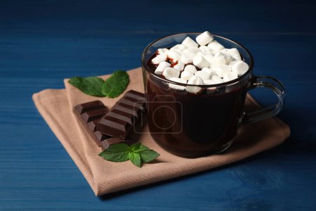 Photo for Glass cup of delicious hot chocolate with marshmallows and fresh mint on blue wooden table - Royalty Free Image