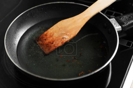 Téléchargez les photos : Poêle à frire avec spatule et huile de cuisson utilisée sur la cuisinière, gros plan - en image libre de droit